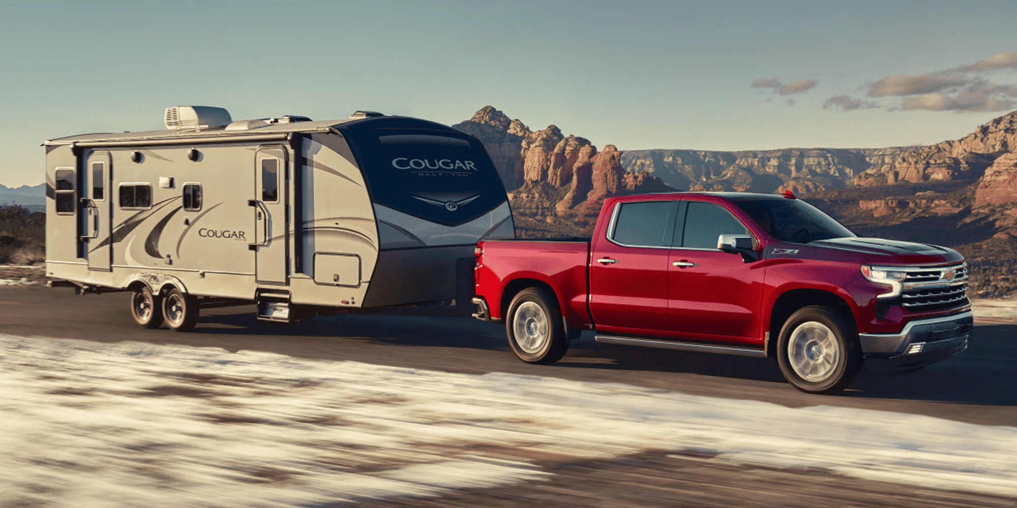 Red Chevrolet Silverado Towing a Recreational Chicle in the desert.